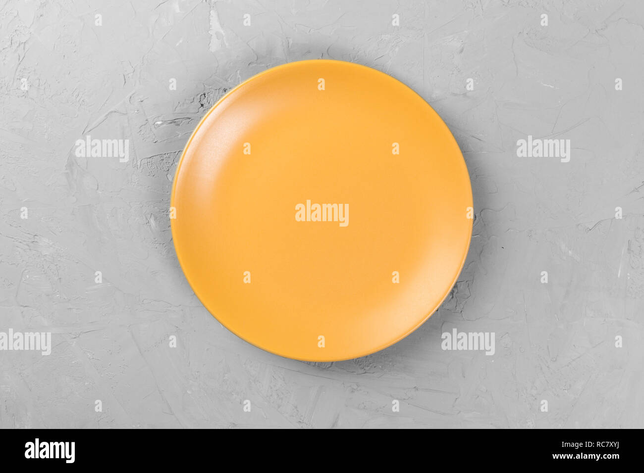 Top view of matte round empty orange dish on dark cement background ...