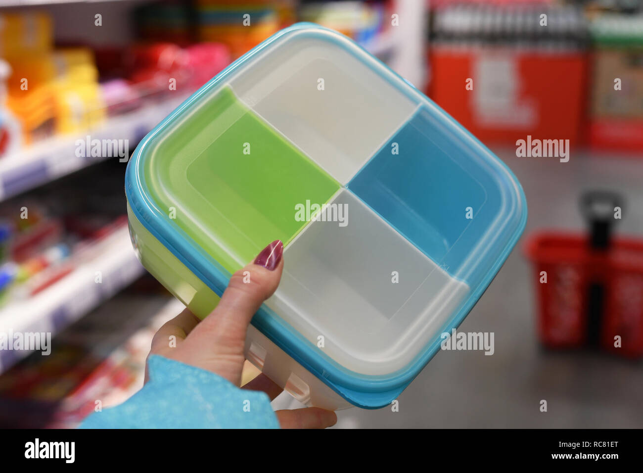 Plastic food container in female hand on shop background Stock Photo