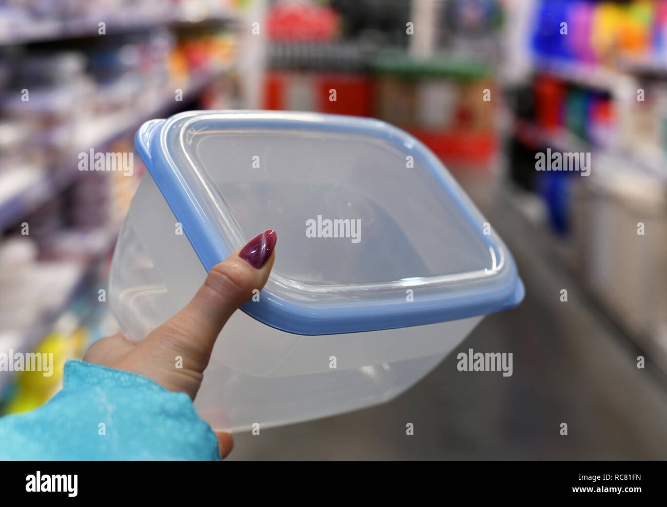 Plastic food container in female hand on shop background Stock Photo