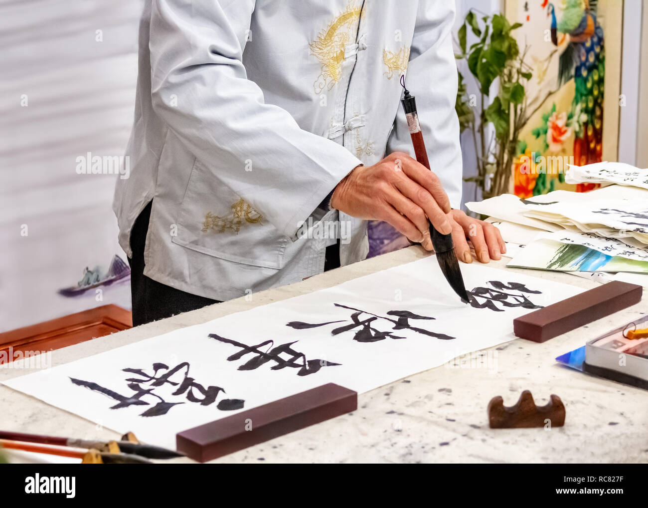 Asian caligraphy. The master of Chinese Caligraphy writes characters and hieroglyphs that read Xin nian kuai le and are translated as Happy New Year. Stock Photo