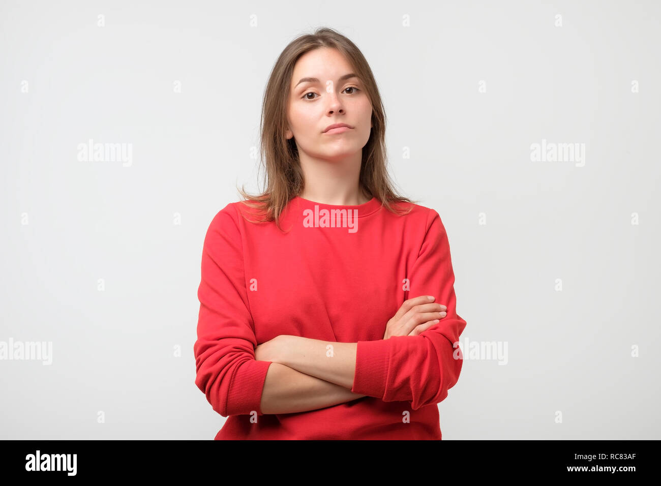 Young serious angry woman in red sweater on a white background Stock Photo