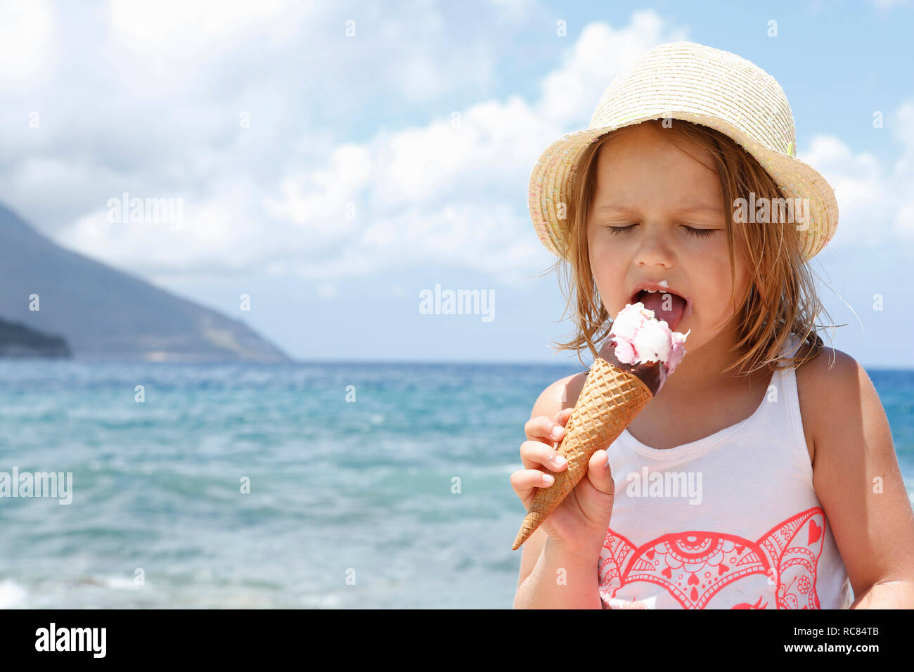 Girl eating ice cream cone on beach, Scopello, Sicily, Italy Stock Photo