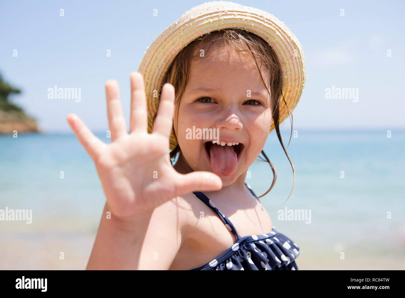 Girl in sunhat sticking out her tongue, portrait, Scopello, Sicily, Italy Stock Photo