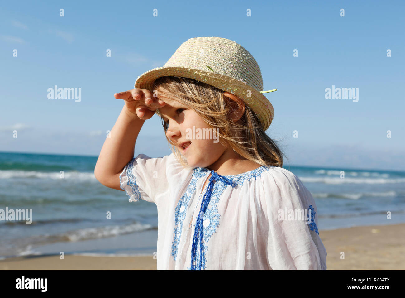 Cute girl on beach shielding her eyes, Castellammare del Golfo, Sicily, Italy Stock Photo