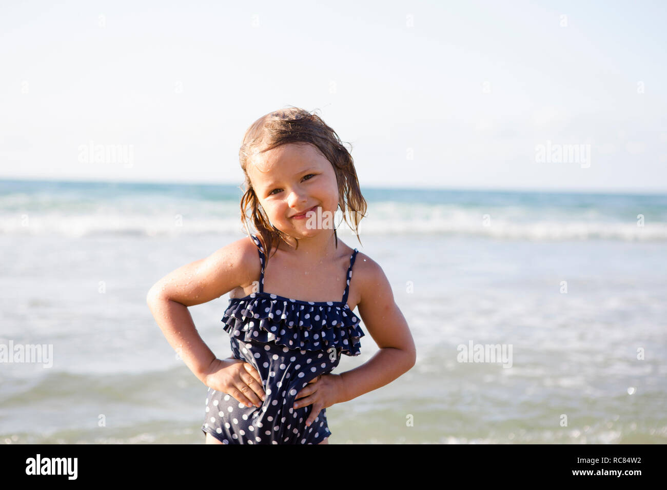 Cute girl on beach in spotted swimming costume, portrait, Castellammare del Golfo, Sicily, Italy Stock Photo