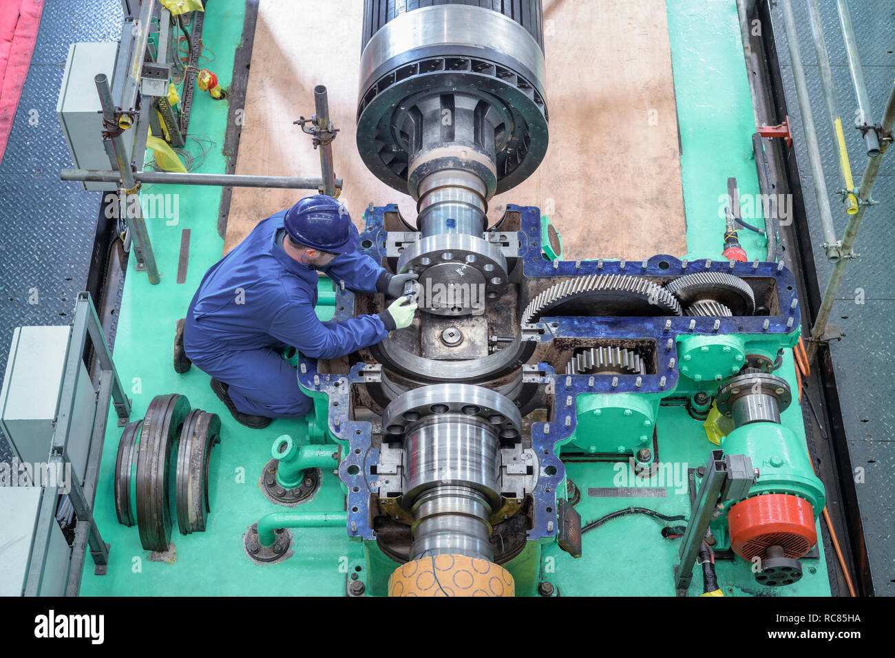Overhead view of engineer inspecting gears on generator in turbine hall of nuclear power station during outage Stock Photo