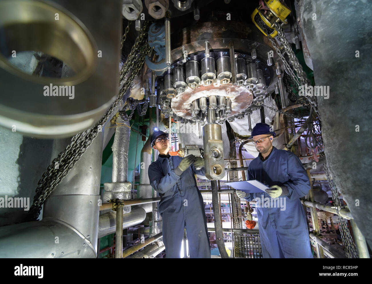 Engineers working in confined space under turbine during outage in nuclear power station Stock Photo
