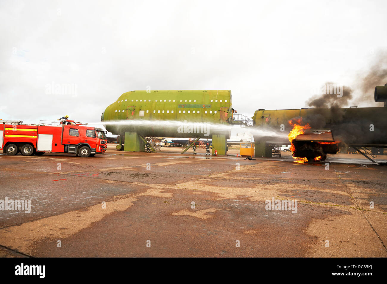 Firemen training, spraying water from fire engine at mock airplane Stock Photo