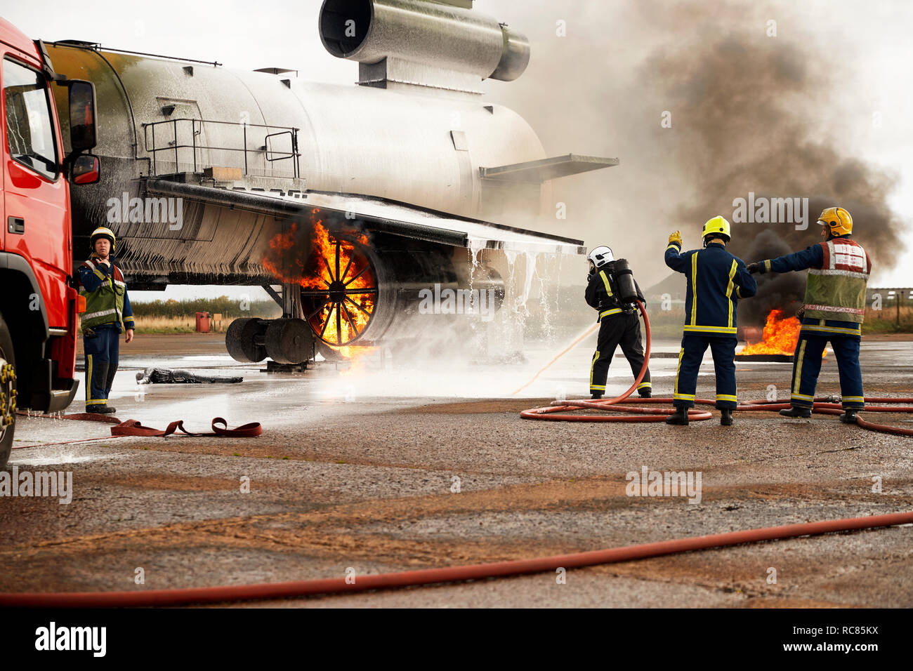 Firemen training, spraying water at mock airplane engine Stock Photo