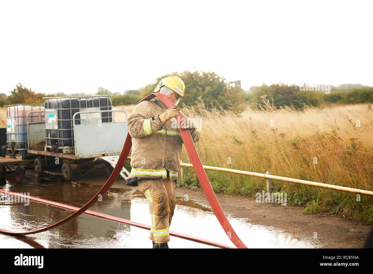 Firemen training, fireman carrying fire hose over his shoulder at training facility Stock Photo