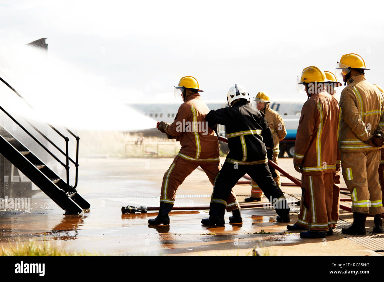 Firemen training, firemen spraying water at training facility Stock Photo