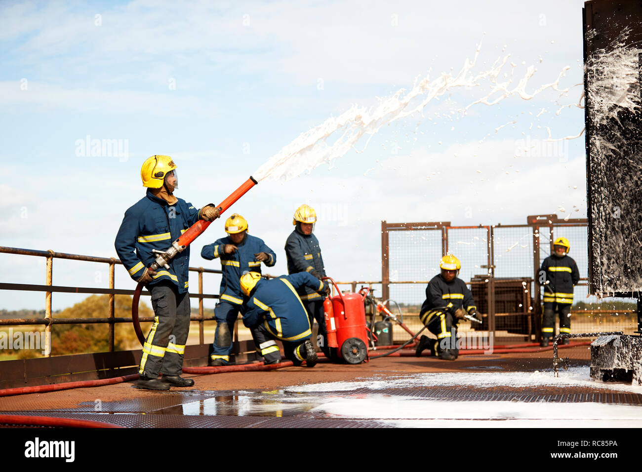 Firemen training, firemen spraying firefighting foam at training facility Stock Photo