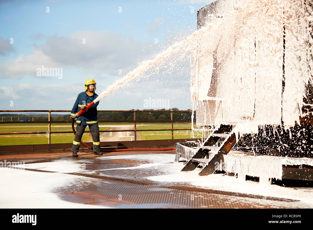 Firemen training, fireman spraying firefighting foam at training facility Stock Photo