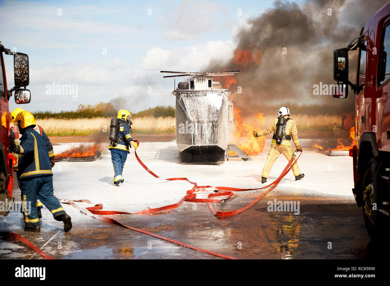 Firemen training, team of firemen extinguishing mock helicopter fire at training facility Stock Photo