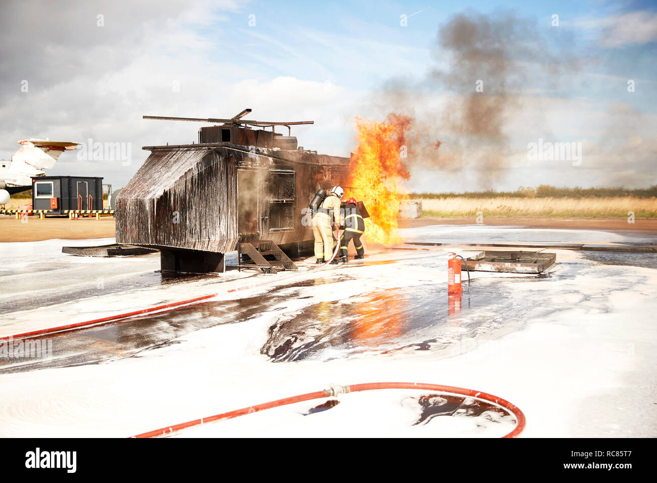 Firemen training, team of firemen spraying firefighting foam at mock helicopter fire at training facility Stock Photo