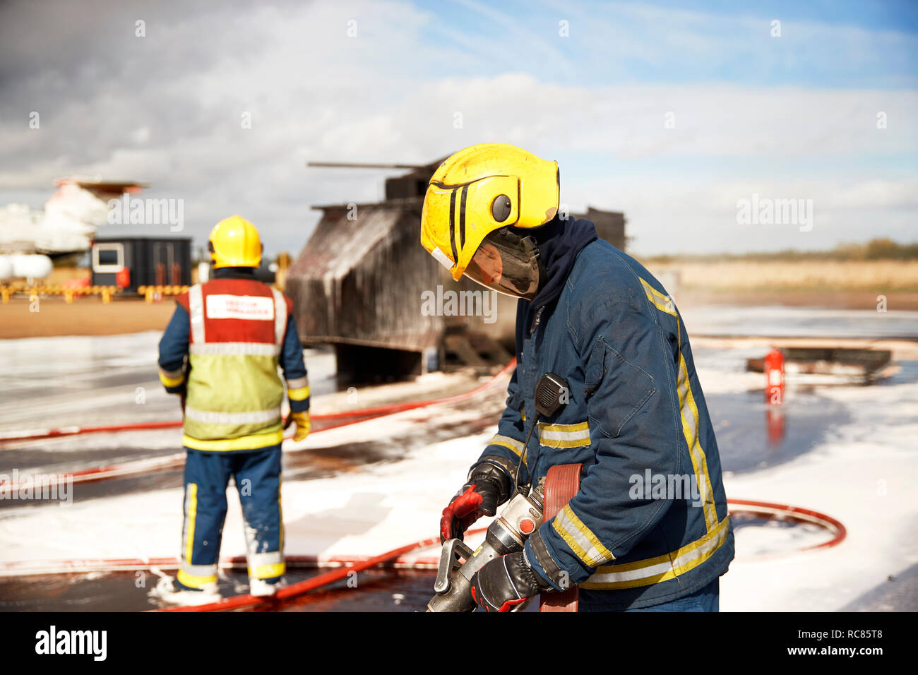 Firemen training, firemen checking fire hose after mock helicopter fire at training facility Stock Photo