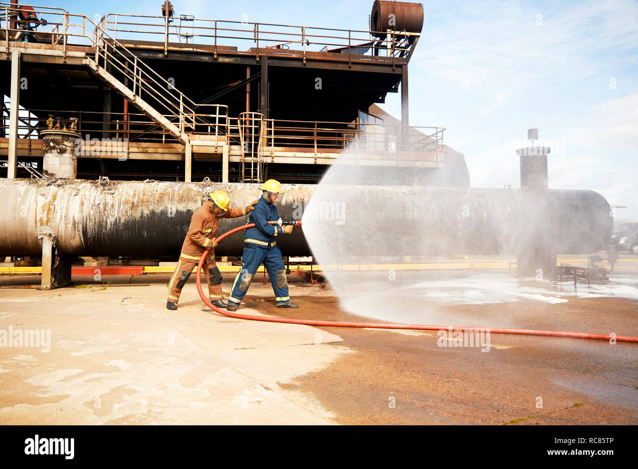 Firemen training, firemen spraying water from fire hose at training facility Stock Photo