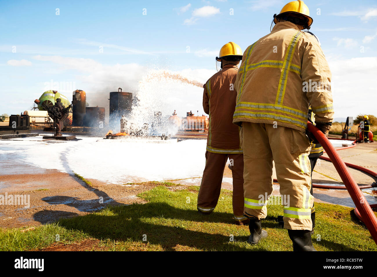 Firemen training, team of firemen spraying firefighting foam at training facility Stock Photo