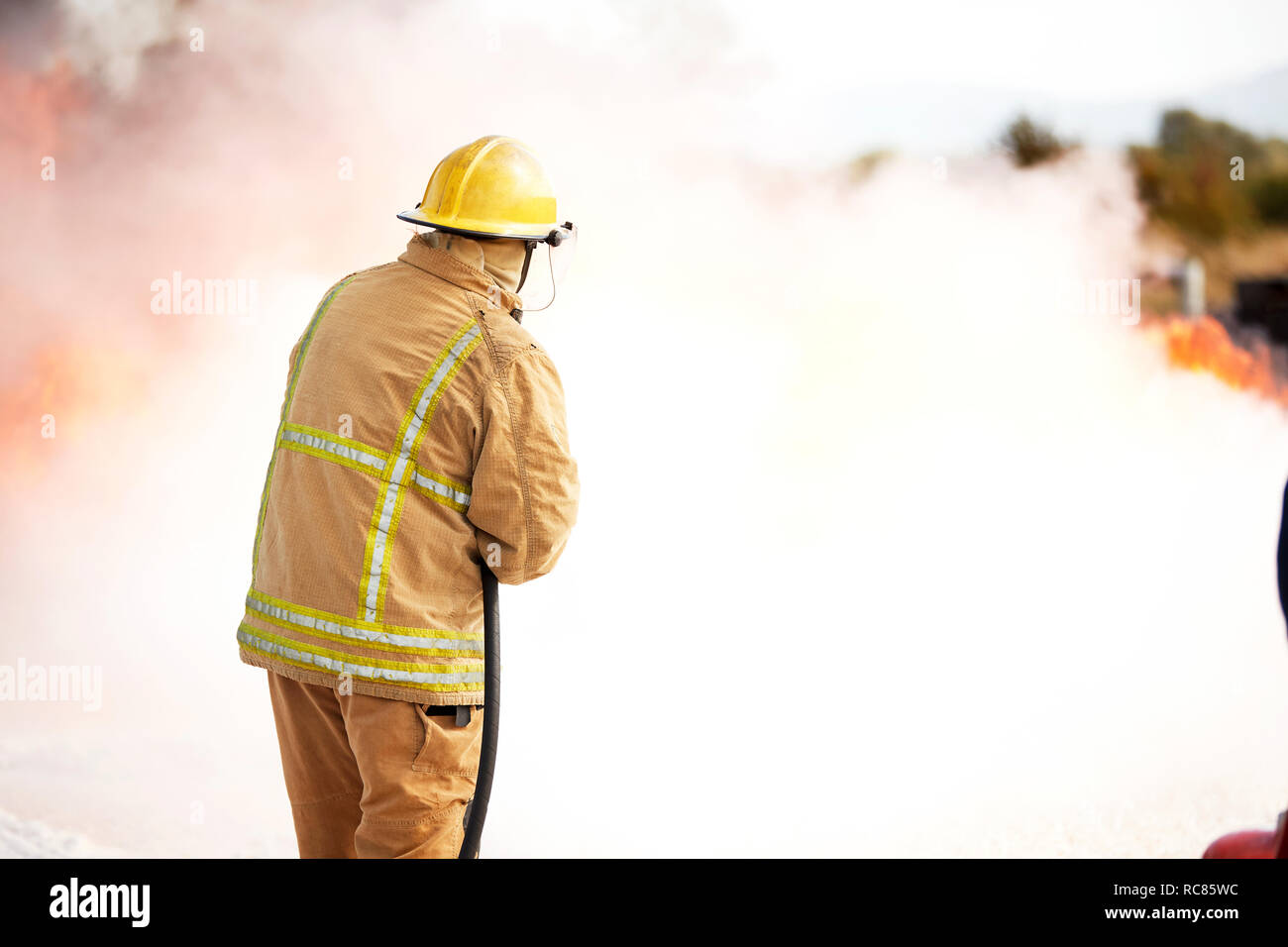 Firemen training, fireman spraying firefighting foam at training facility Stock Photo