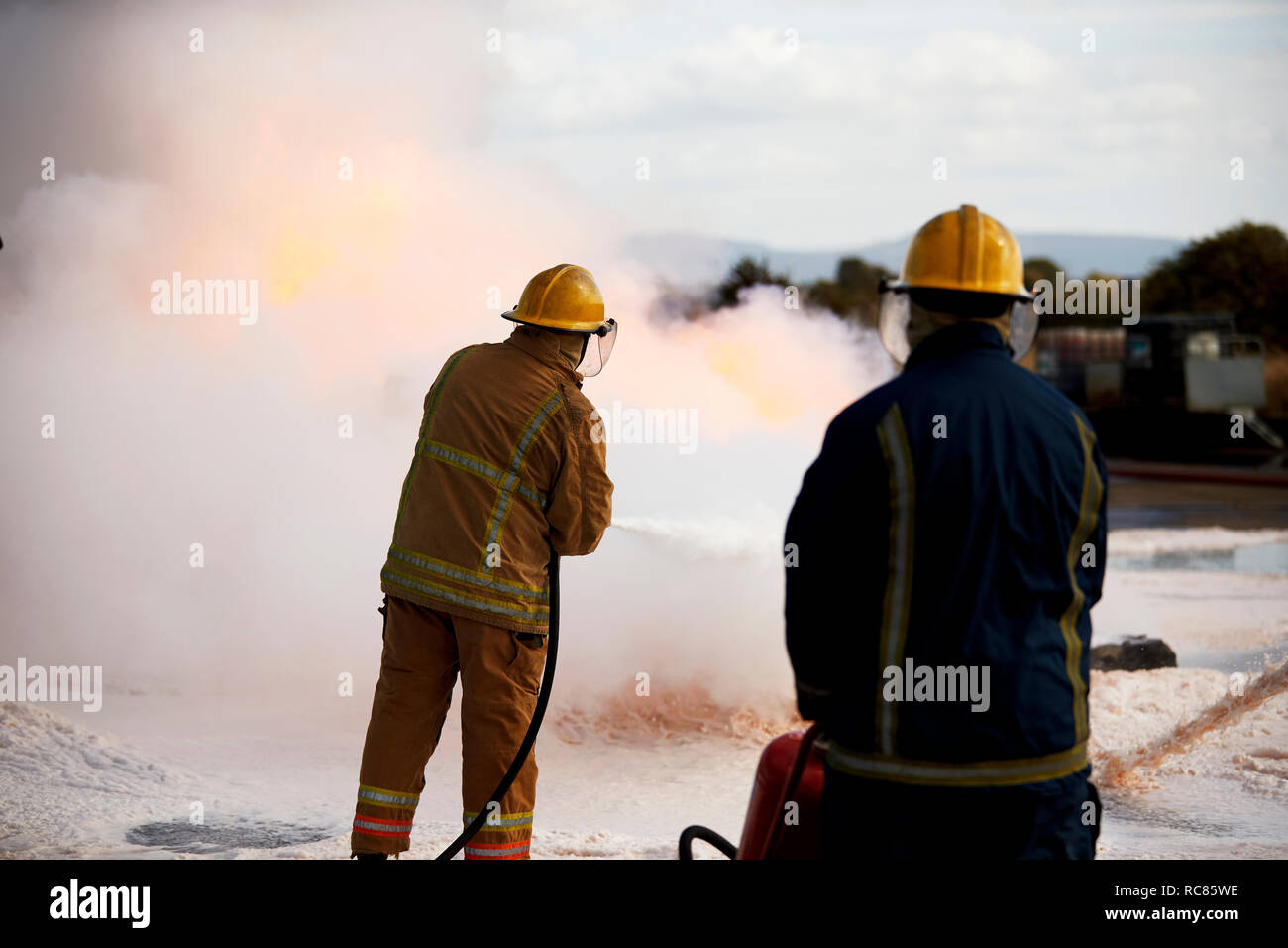 Firemen training, firemen spraying firefighting foam at training facility Stock Photo