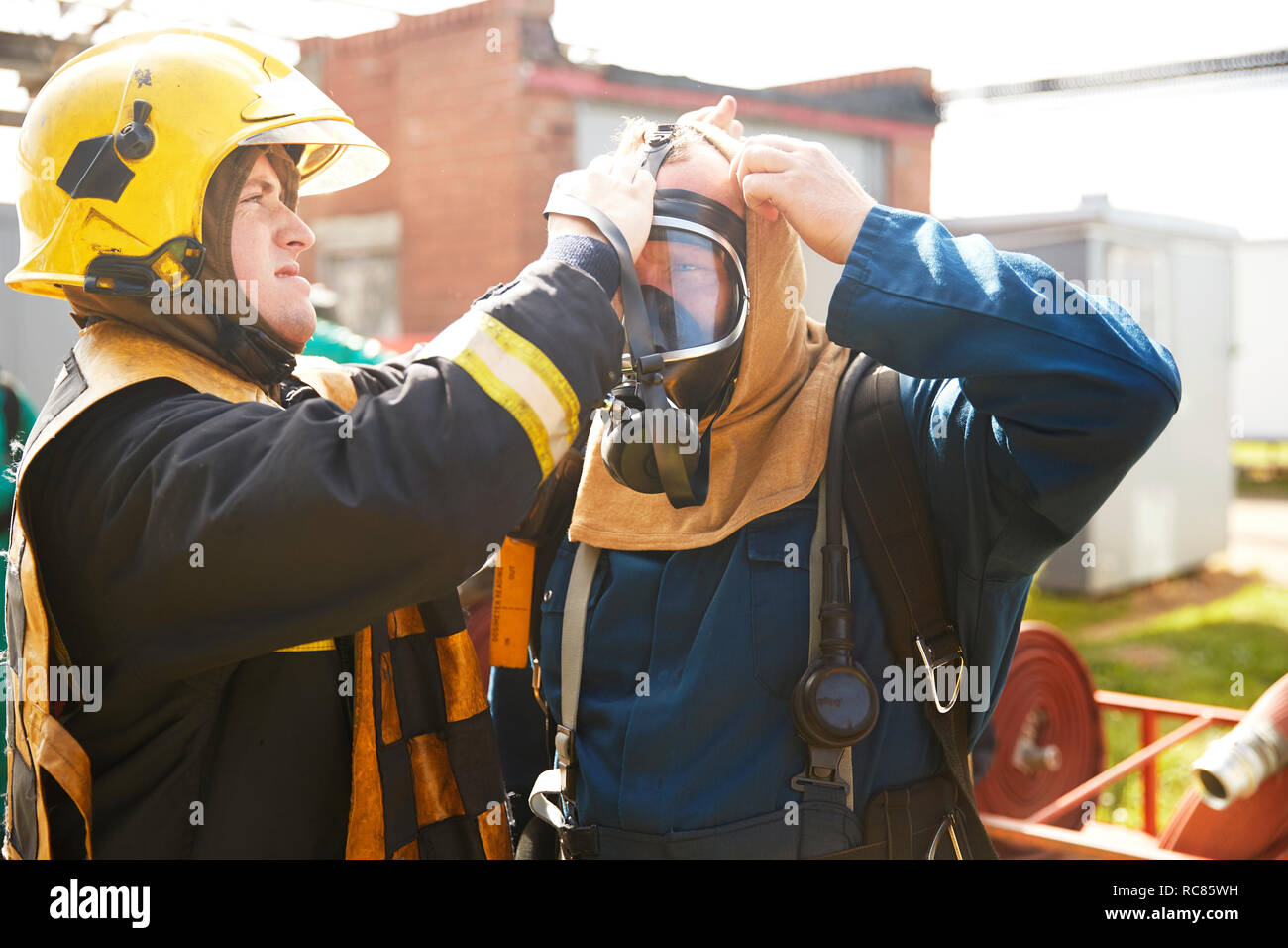 Supervisor helping fireman with breathing apparatus at training
