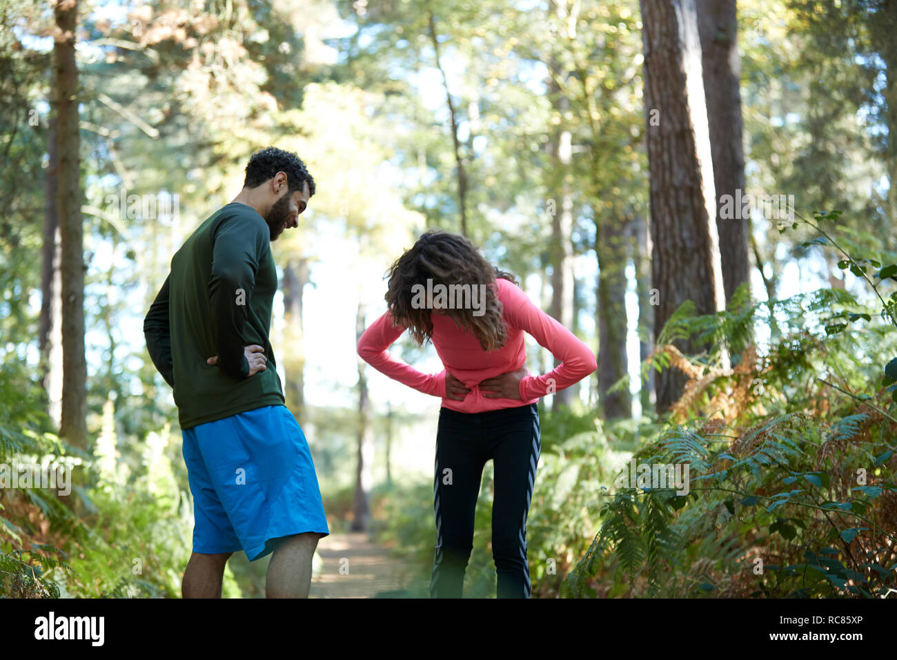 Exhausted male and female runners taking a break in forest Stock Photo