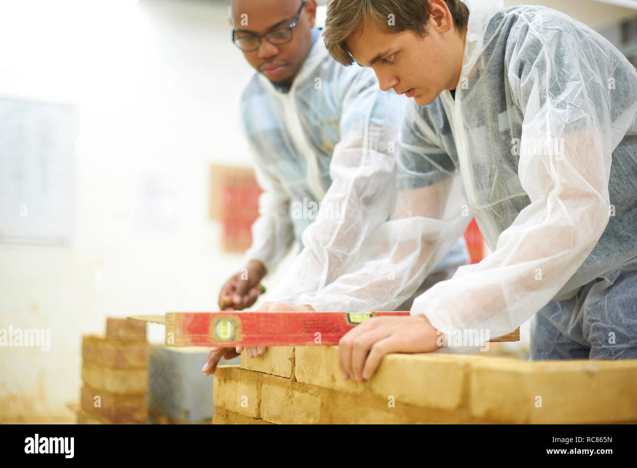 Male higher education students building brick wall in college workshop Stock Photo