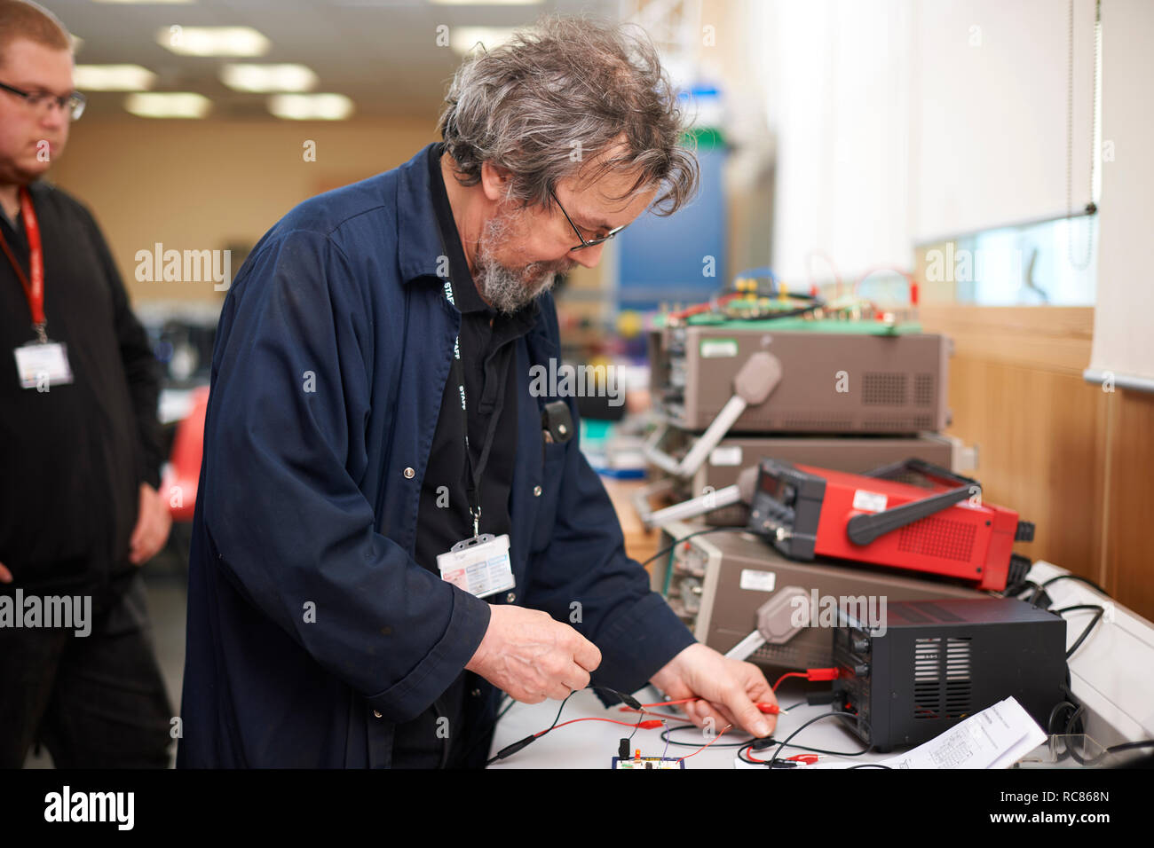 Lecturer preparing electrical instrument, student in background Stock Photo