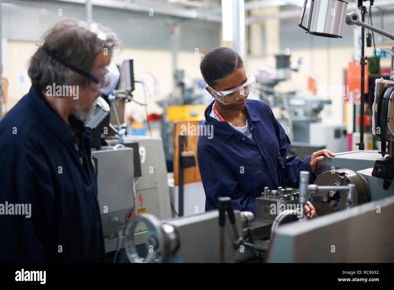 Lecturer teaching student to operate machine in workshop Stock Photo