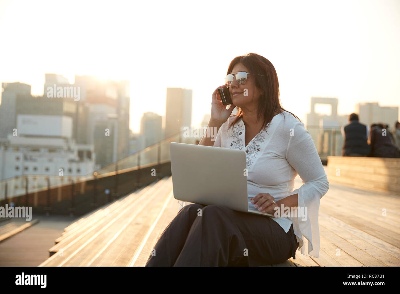 Businesswoman using laptop and smartphone on steps, Seoul, South Korea Stock Photo