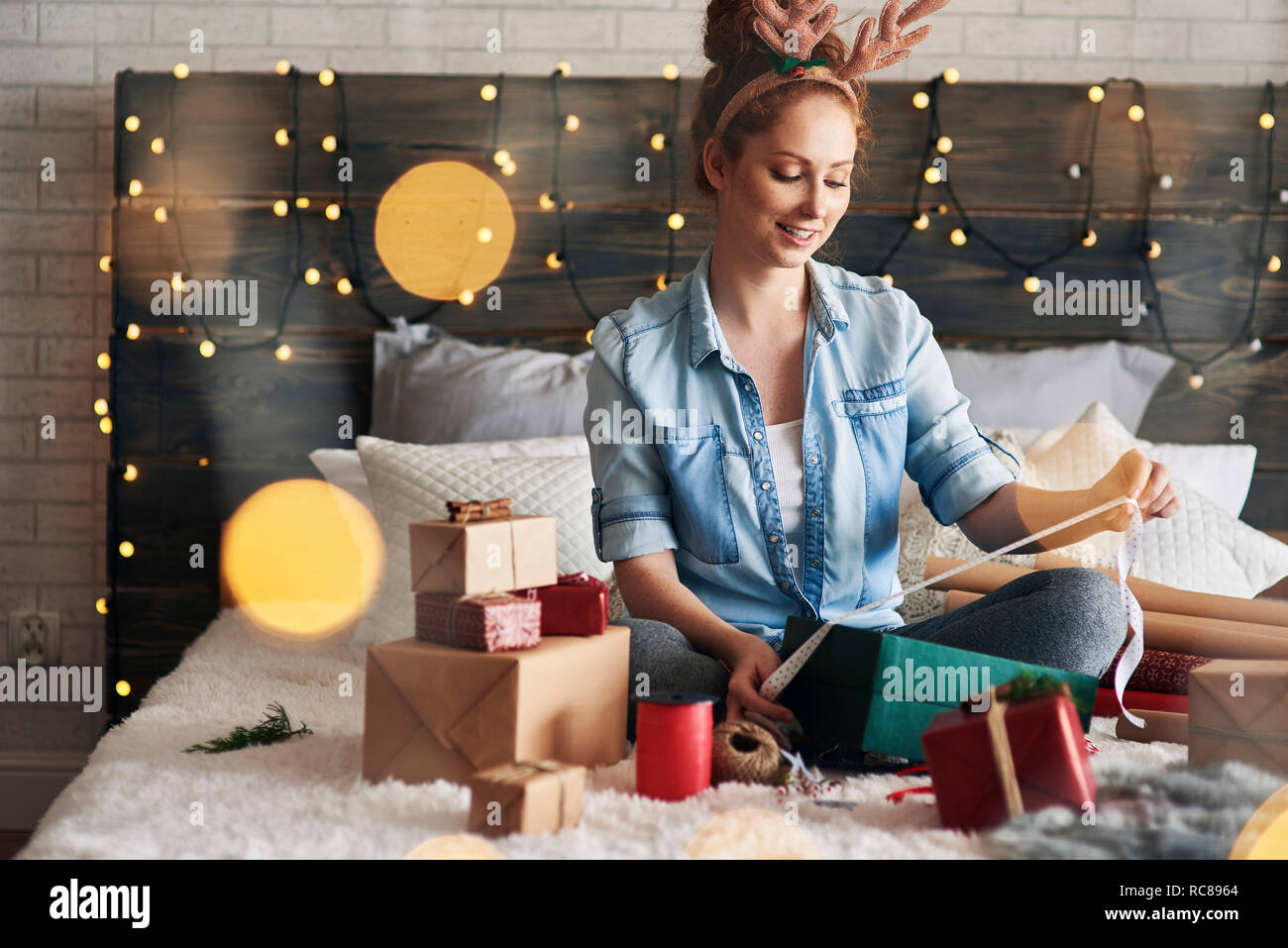 Woman wrapping Christmas presents on bed Stock Photo