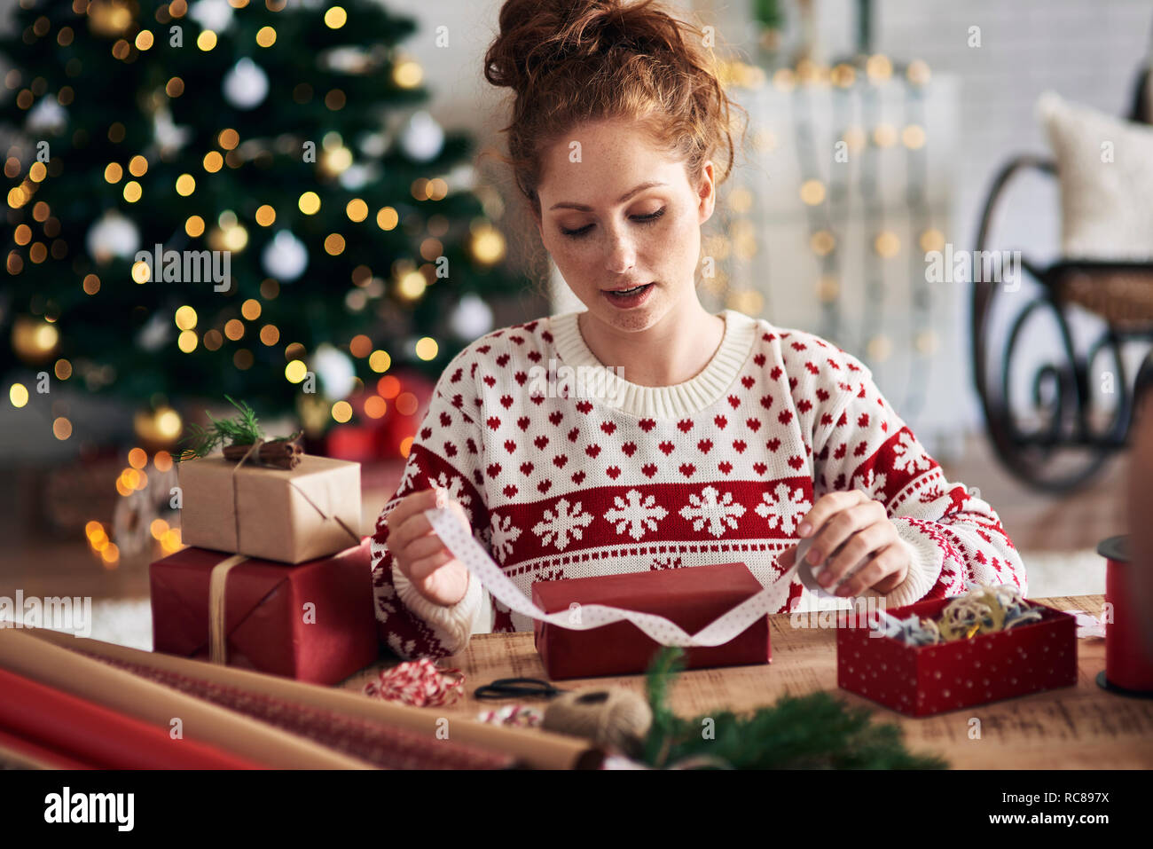 Woman tying ribbon on Christmas present Stock Photo