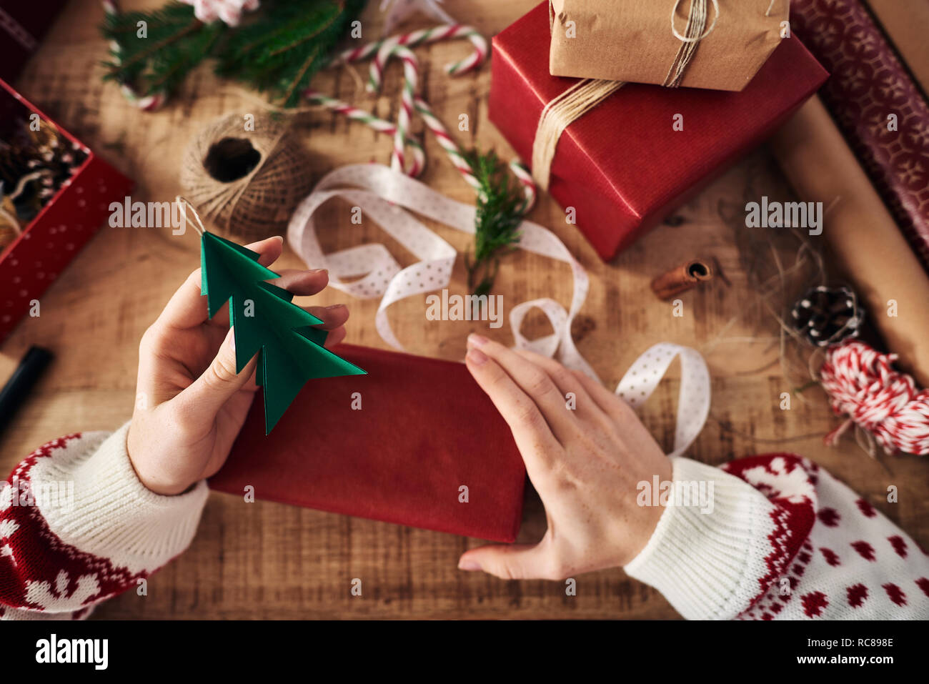 Woman attaching Christmas tree shaped decoration on Christmas present Stock Photo