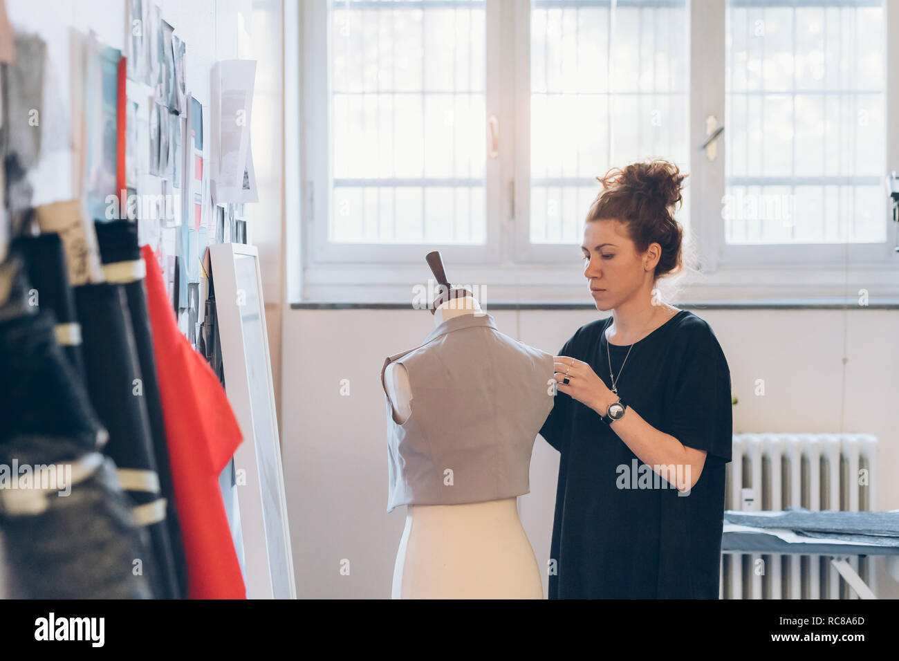 Fashion designer pinning garment onto dressmaker's dummy Stock Photo