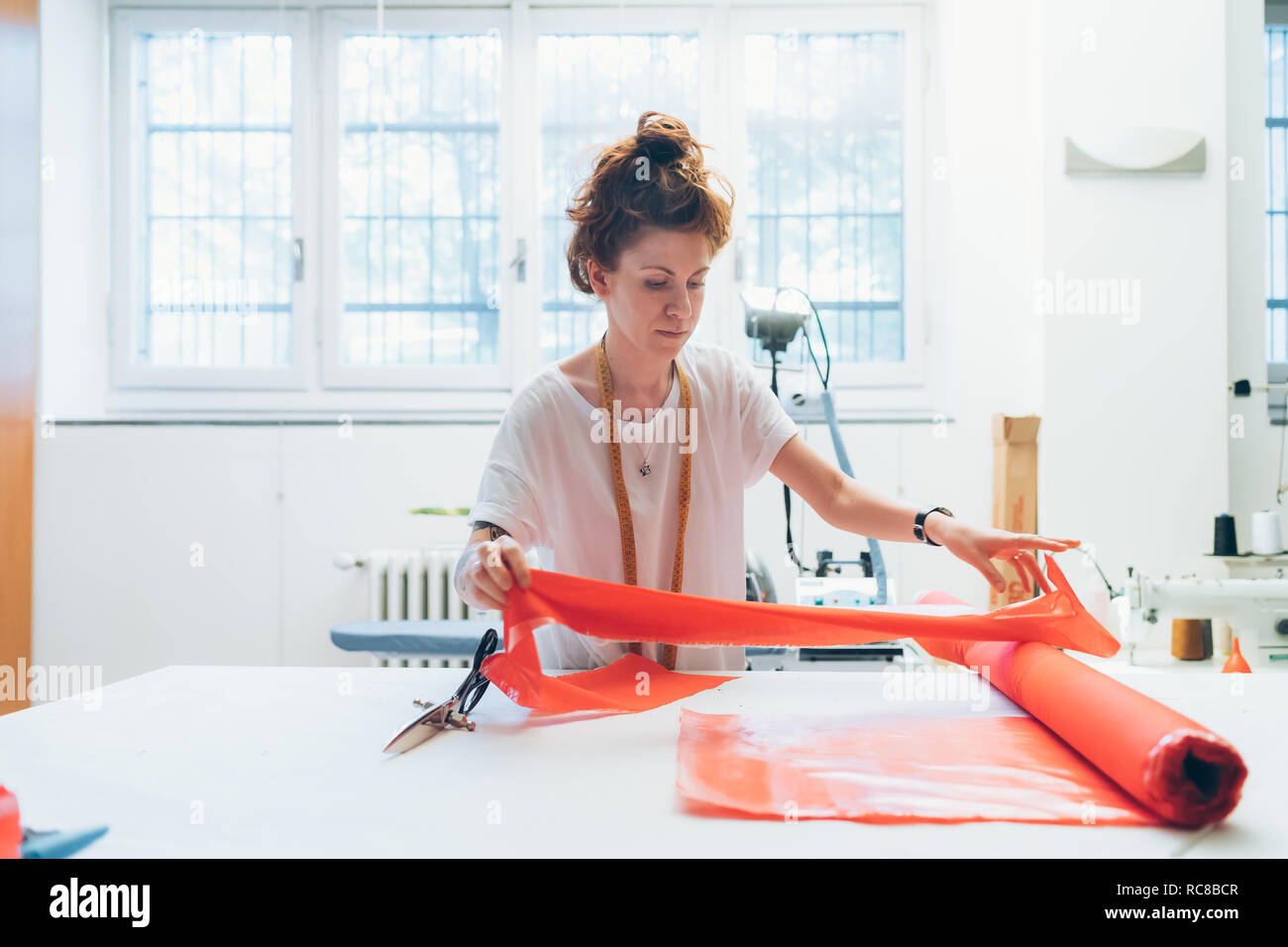 Fashion designer unrolling textile on workbench Stock Photo