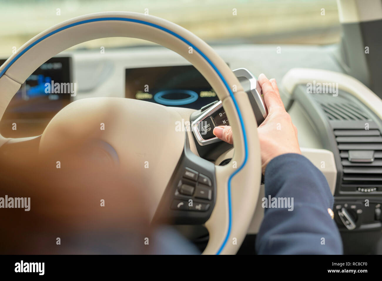 Woman pressing start button on electric car Stock Photo