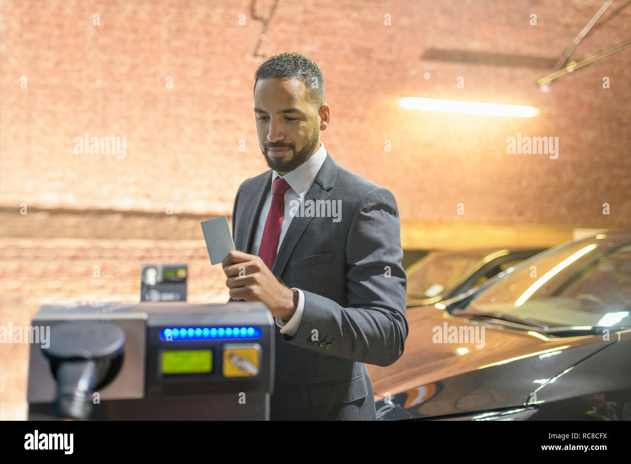 Businessman using access card at electric vehicle charging station, Manchester, UK Stock Photo