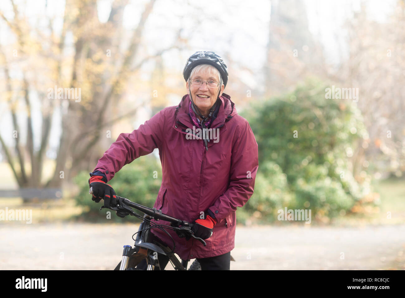 Senior woman on bicycle in park Stock Photo