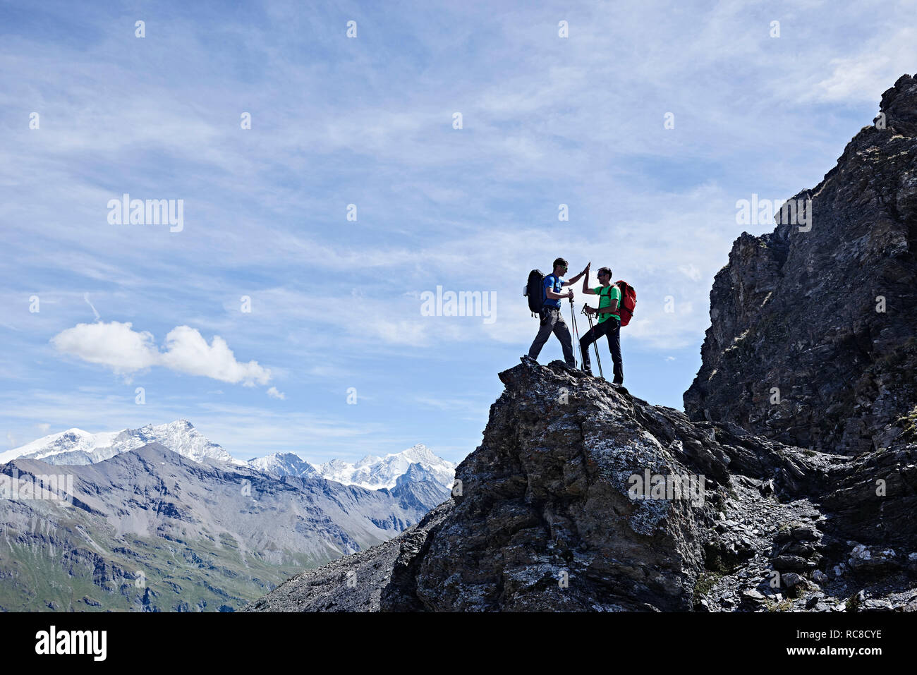 Hikers high fiving on peak of rock, Mont Cervin, Matterhorn, Valais, Switzerland Stock Photo