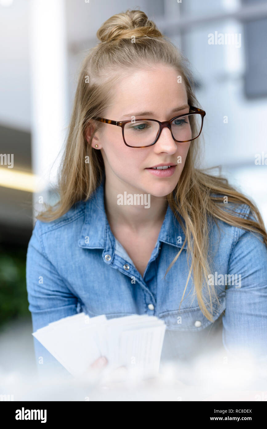 Woman contemplating colour charts in hand Stock Photo