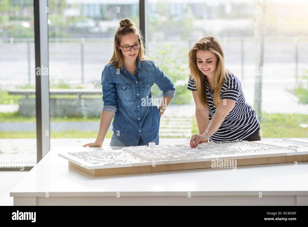 Colleagues brainstorming over architectural model Stock Photo