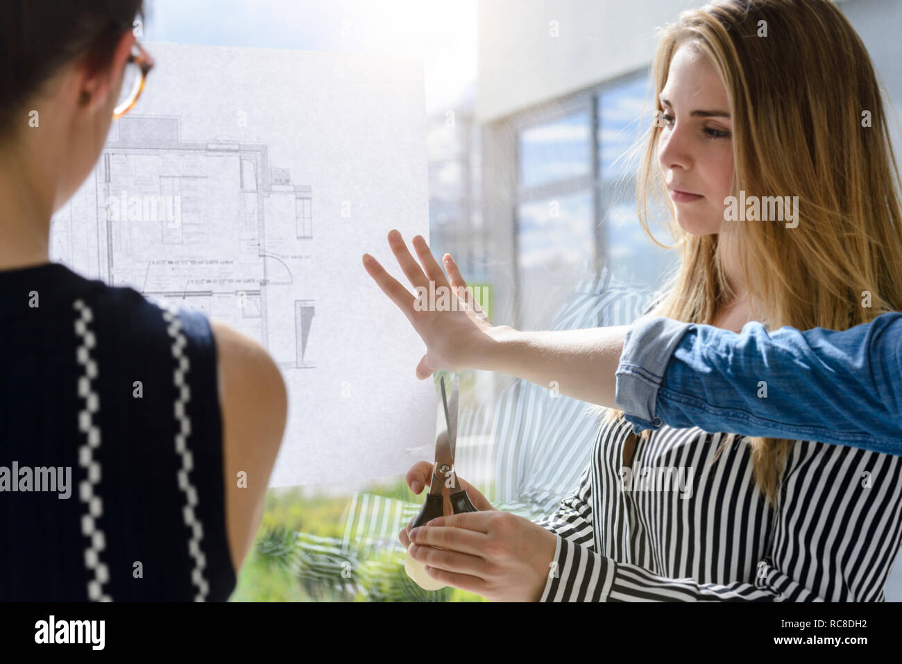 Colleagues discussing plans on glass wall Stock Photo