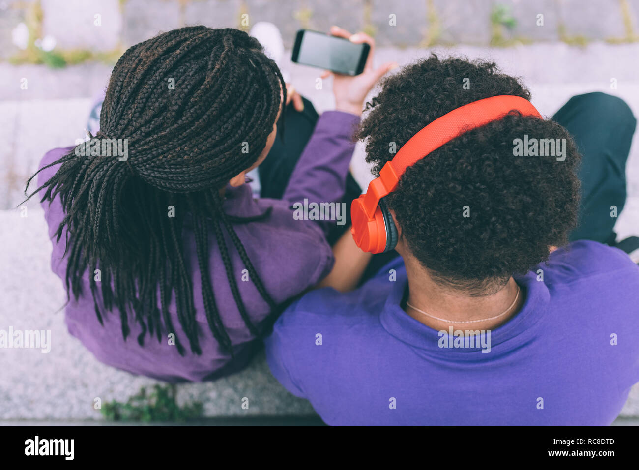 Brother and sister watching footage on mobile phone together Stock Photo