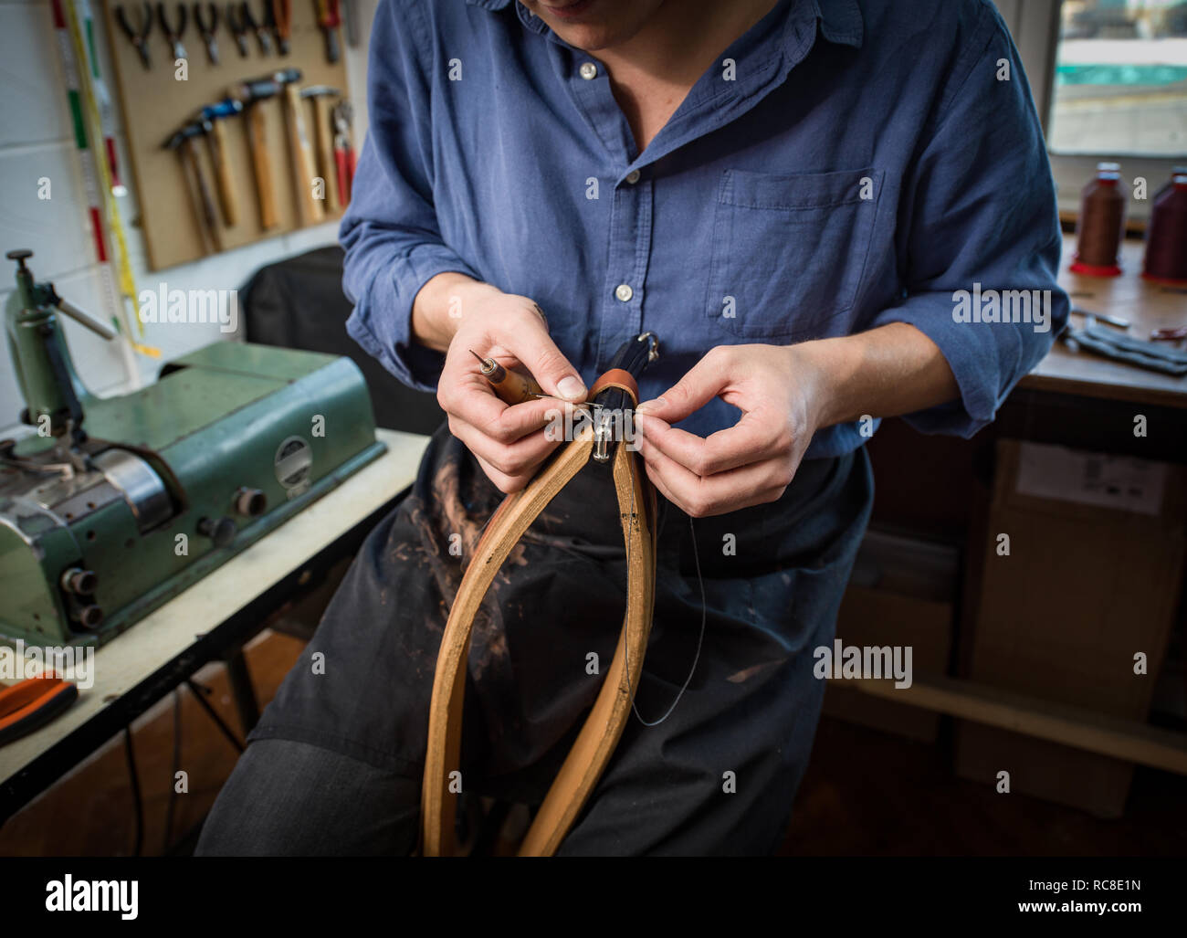 Leatherworker stitching leather in workshop, mid section Stock Photo