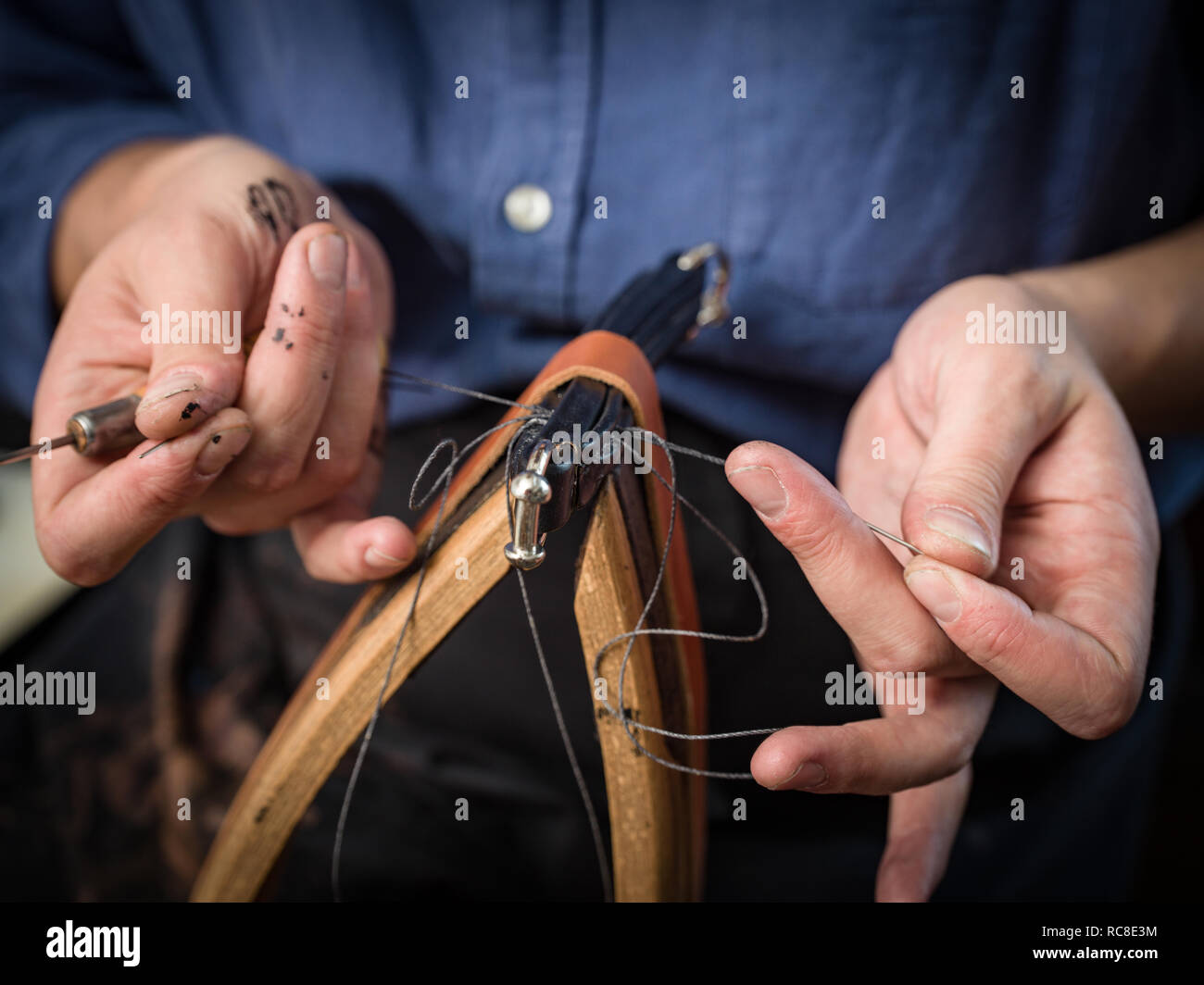 Leatherworker stitching handbag in workshop, close up of hands Stock Photo