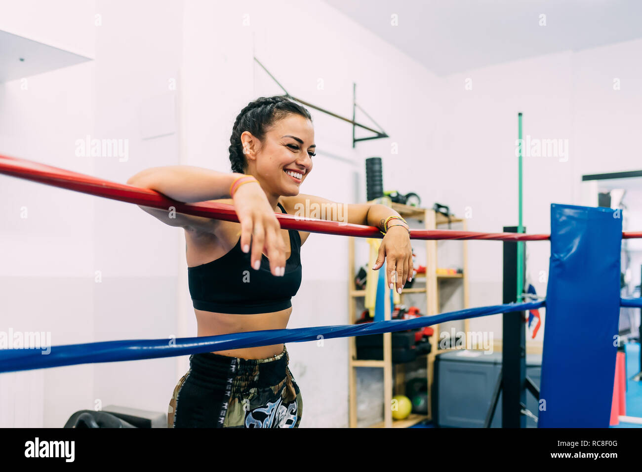 Laughing female boxer leaning over boxing ring ropes Stock Photo