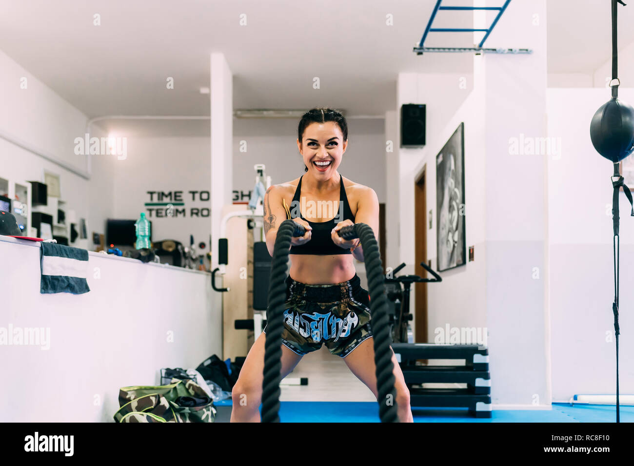 Woman using rope whips during workout in gym Stock Photo