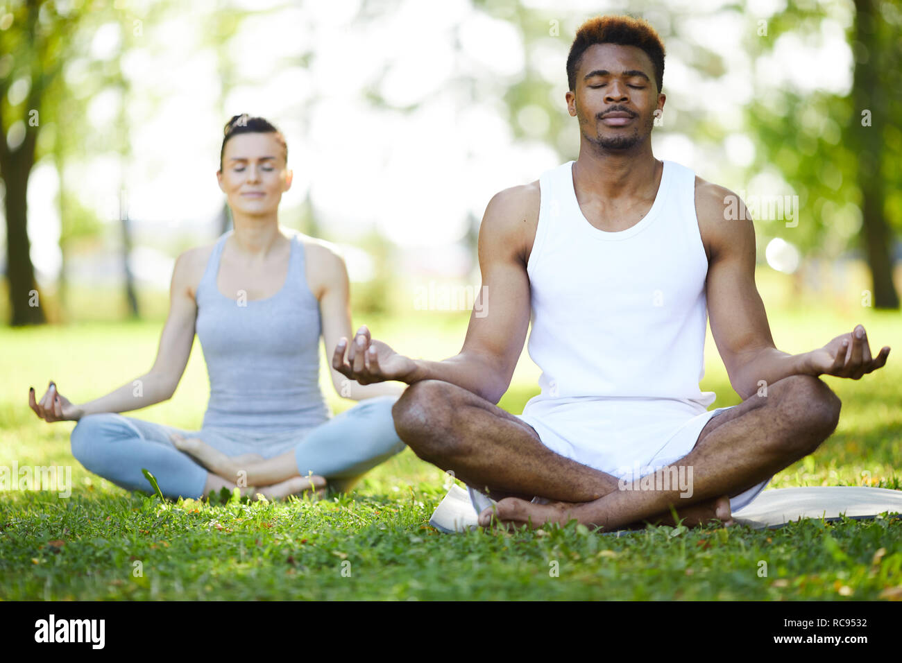 Concentrated yoga students meditating in park Stock Photo