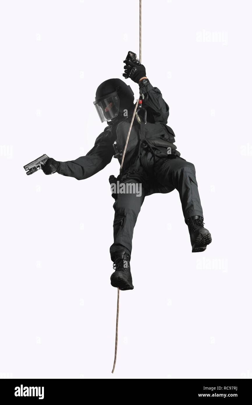Police, Special Task Force, SEK, police officer wearing full protective gear holding a pistol while abseiling on a rope Stock Photo