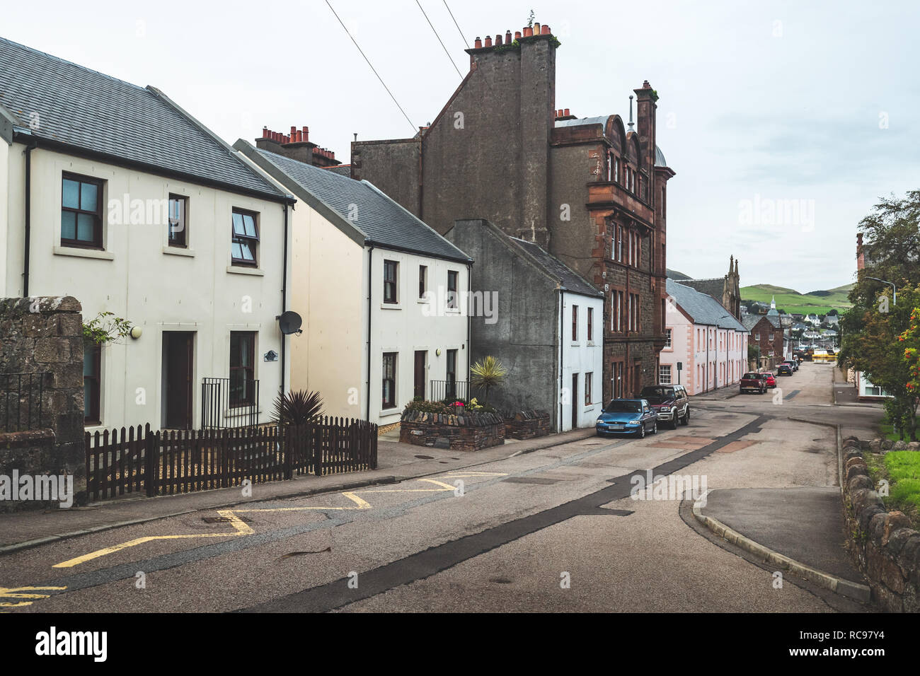 Ancient buildings on the cozy street. Northern Ireland. Small town scenery. Historic stone houses on the attractive narrow street. Vintage retro style. Victorian epoque. The landscape in brown tints. Stock Photo